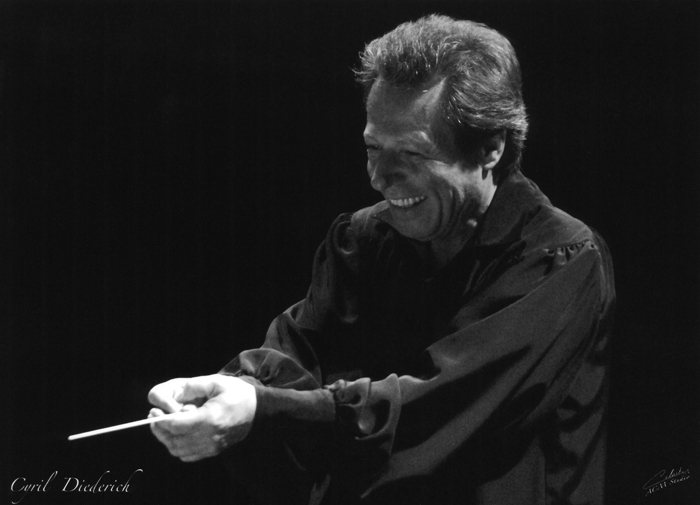 Cyril Diederich, holding his conductor's baton, smiling